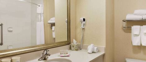 Une salle de bain d’hôtel équipée d’un lavabo, d’un miroir, d’un porte-serviettes et de toilettes.