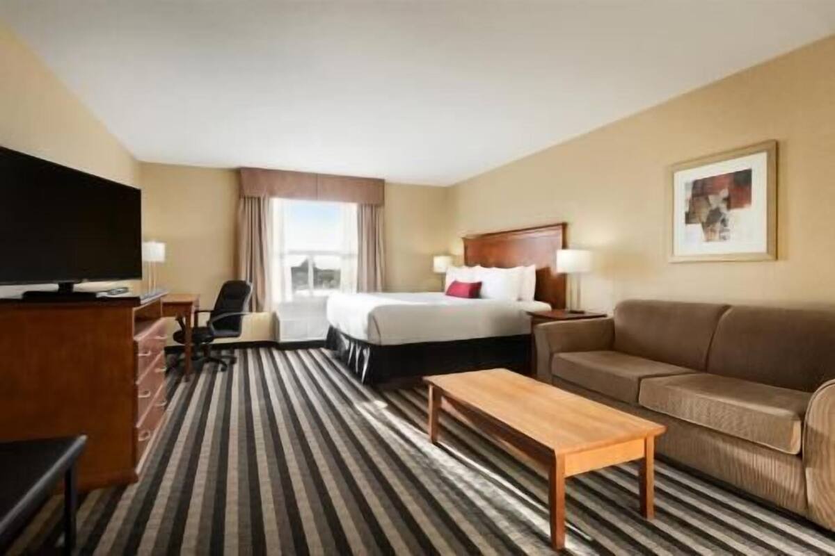 Una habitación de hotel con cama, escritorio, televisor, sofá y mesa de centro.