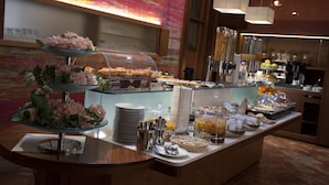 Zona de bufé con diversas opciones de comida y una decoración floral.