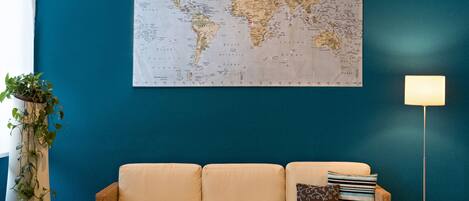 A living room with a large world map on the wall, a beige sofa, a wooden coffee table, and a floor lamp.
