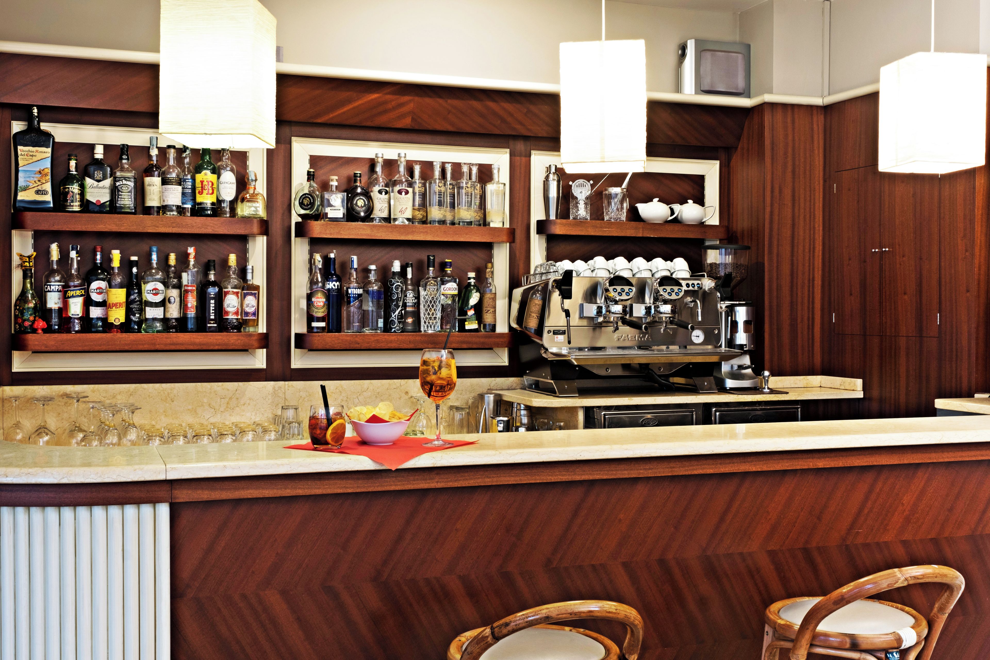 Eine Bar mit Regalen voller Spirituosen, einer Kaffeemaschine und Sitzgelegenheiten.