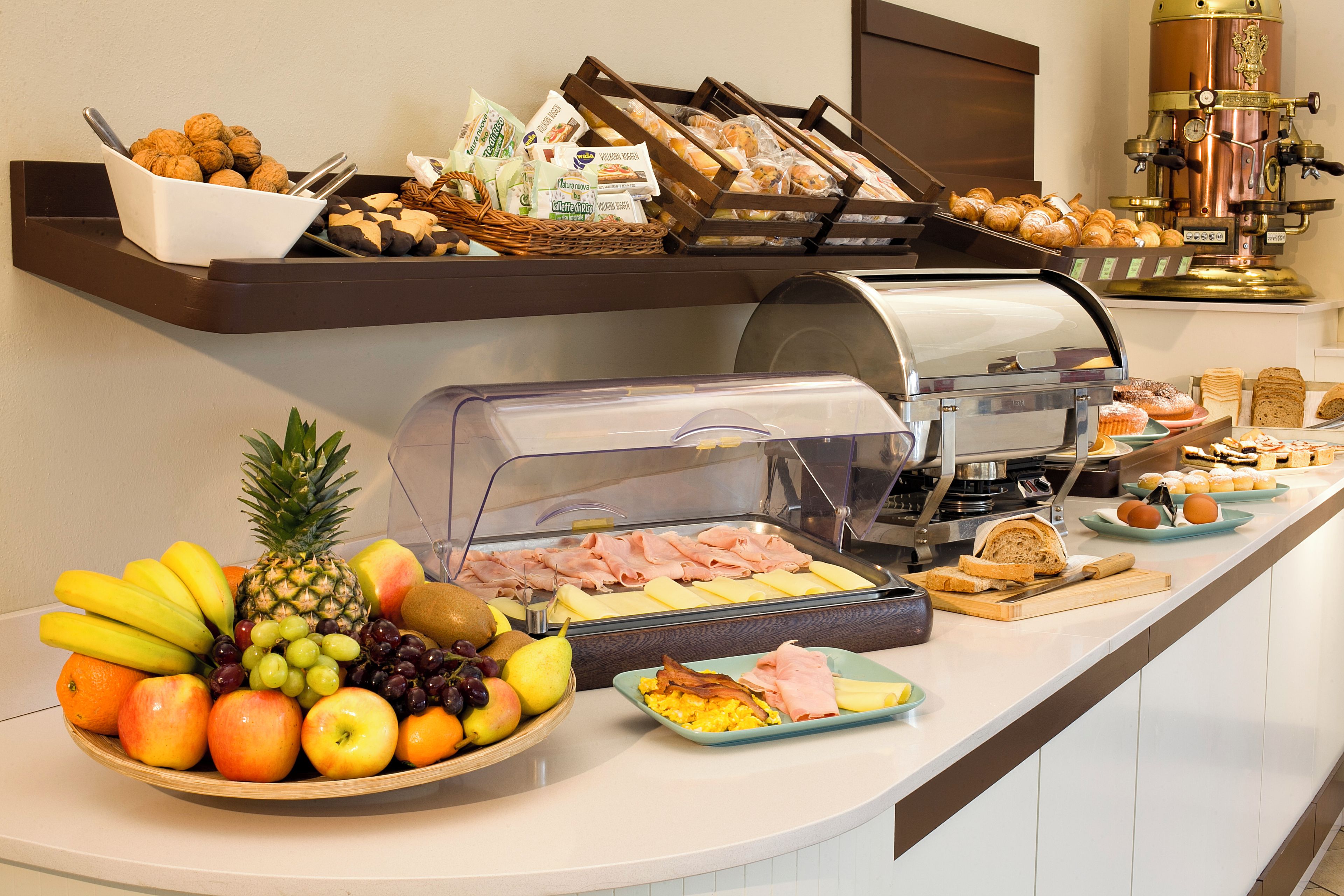 A buffet with a variety of food items including fruits, meats, and pastries.