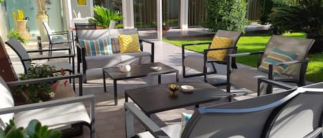 An outdoor patio area with multiple seating options, including sofas and chairs, arranged around tables.