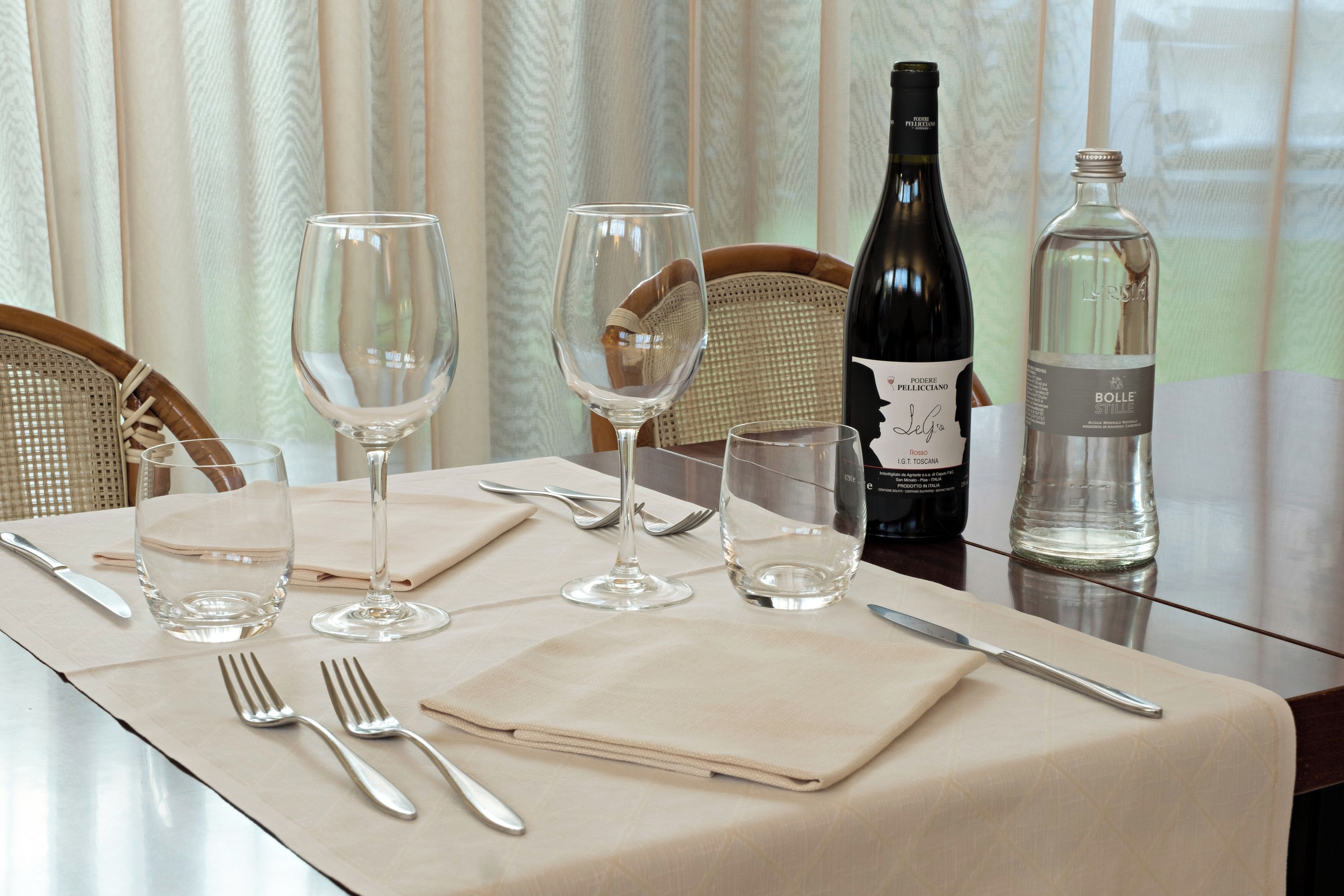 Une table à manger dressée avec des verres à vin, une bouteille de vin et une bouteille d’eau.