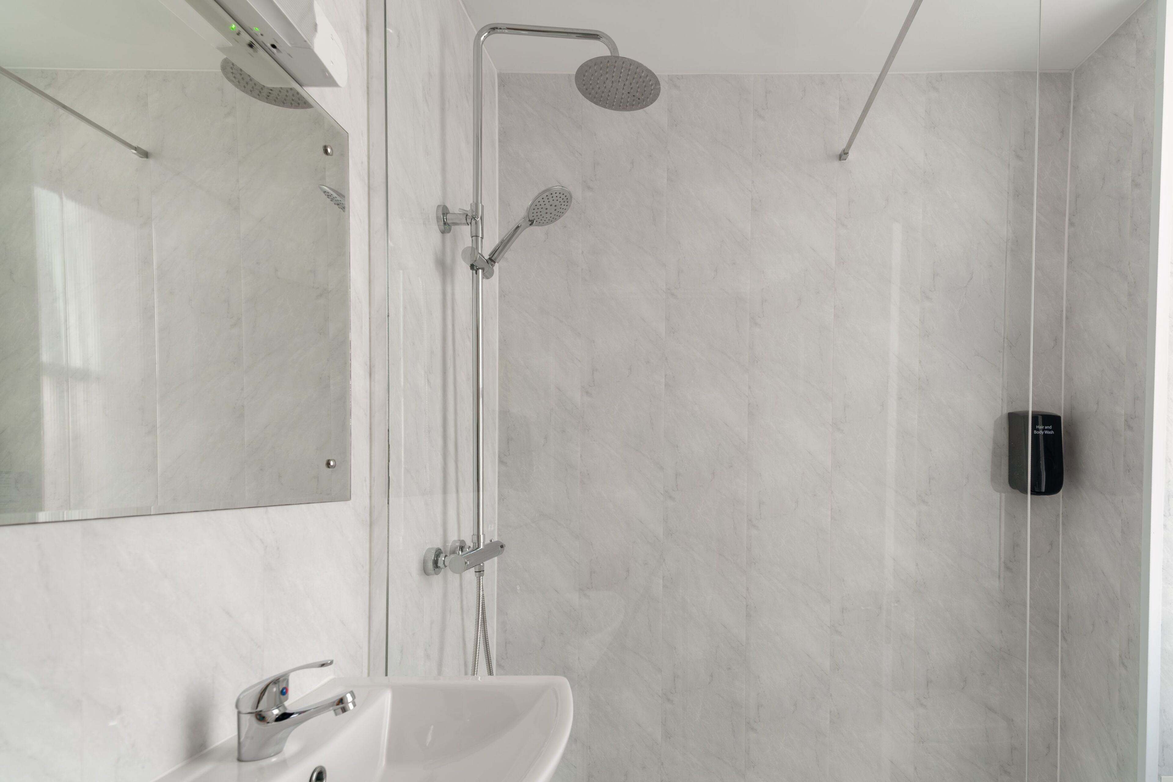 Un baño moderno con ducha, lavabo y espejo.