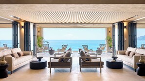 A spacious living area with a view of the sea, featuring sofas, armchairs, and round tables. - Ella Alkyna – Adults Only (Corfu)