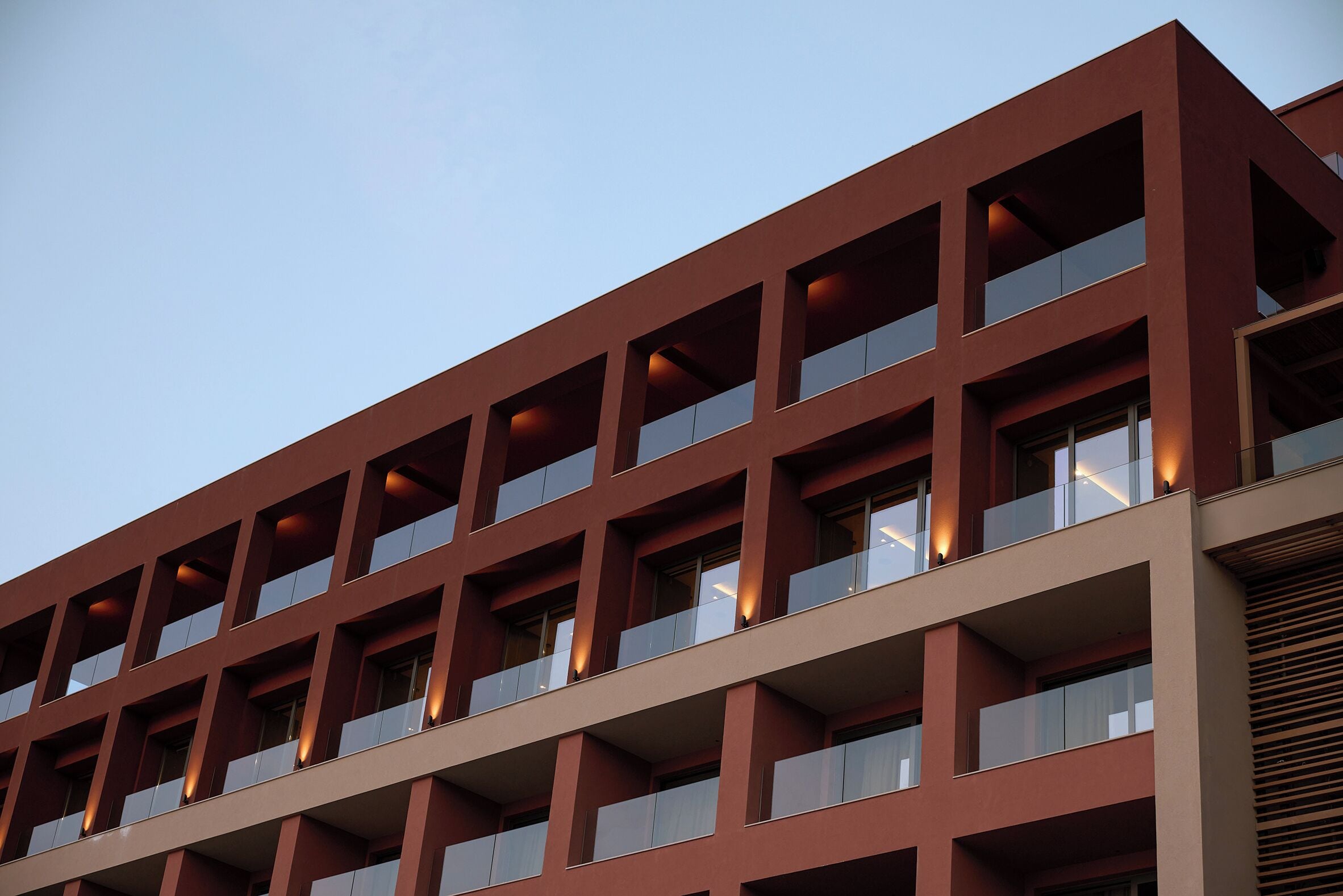 A multi-story building with a modern architectural design, featuring balconies and large windows.