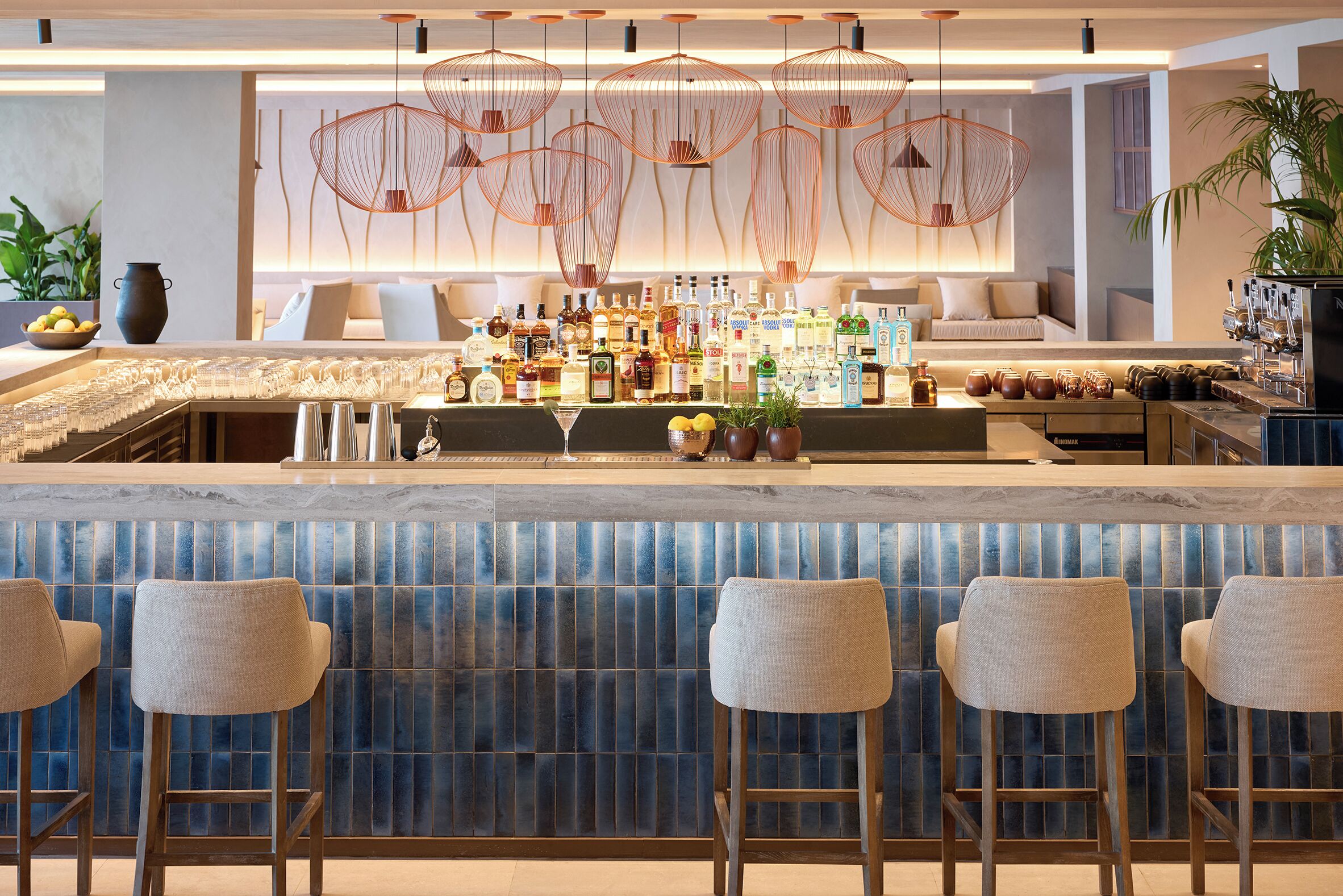 A bar area with a marble countertop, multiple liquor bottles, and bar stools.