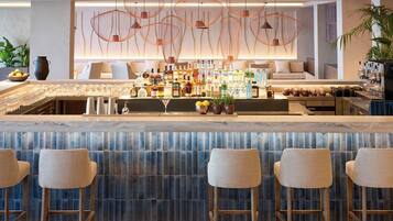 A bar area with a marble countertop, multiple liquor bottles, and bar stools.
