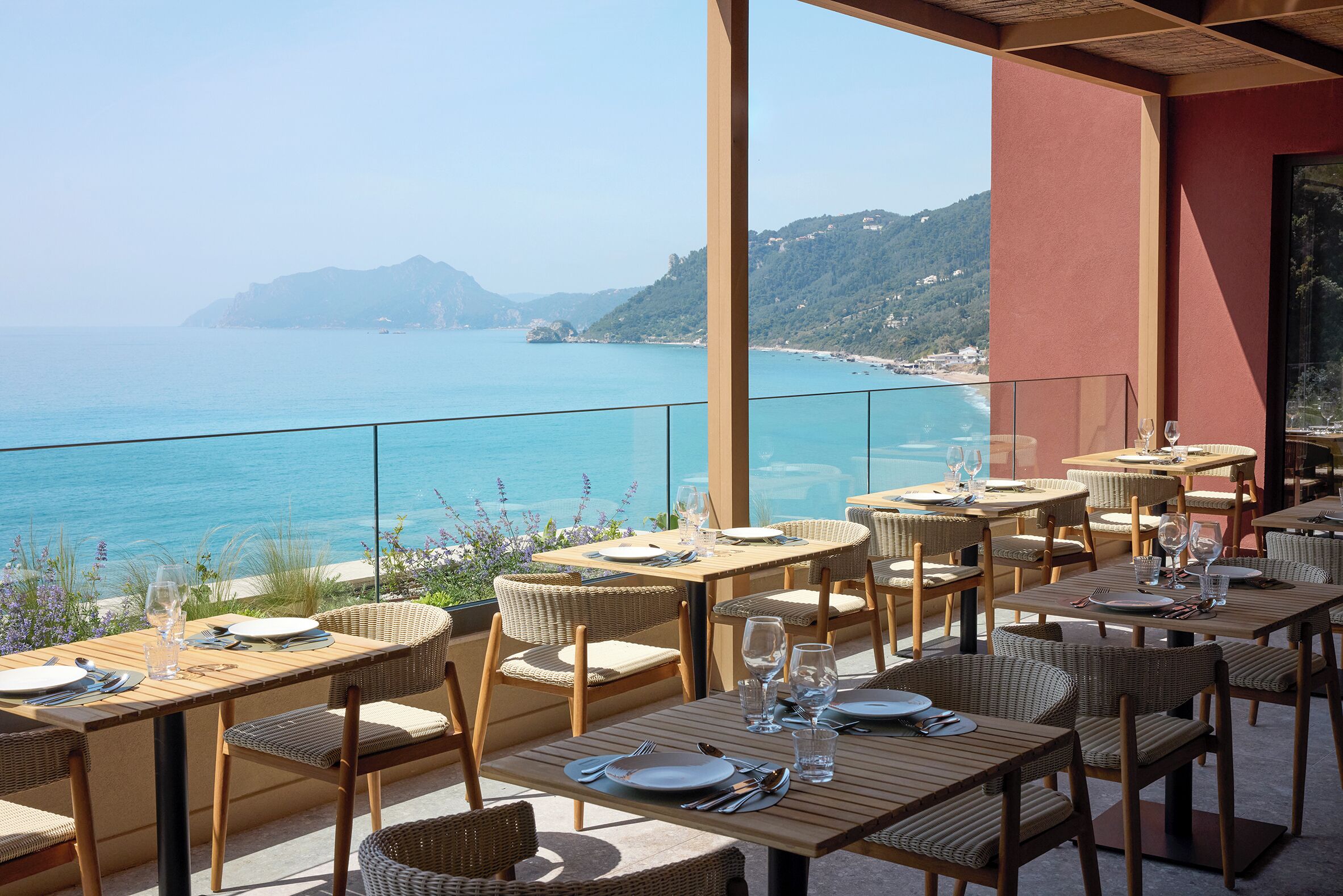 Un área de comedor al aire libre con mesas y sillas, con vistas a la costa.