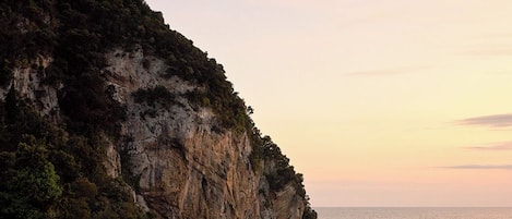 Paisaje costero con un acantilado escarpado y vista al mar al atardecer.
