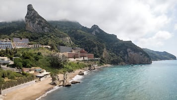 Ein Küstenhotel mit mehreren Gebäuden, einem Strand und einer Bergkulisse.