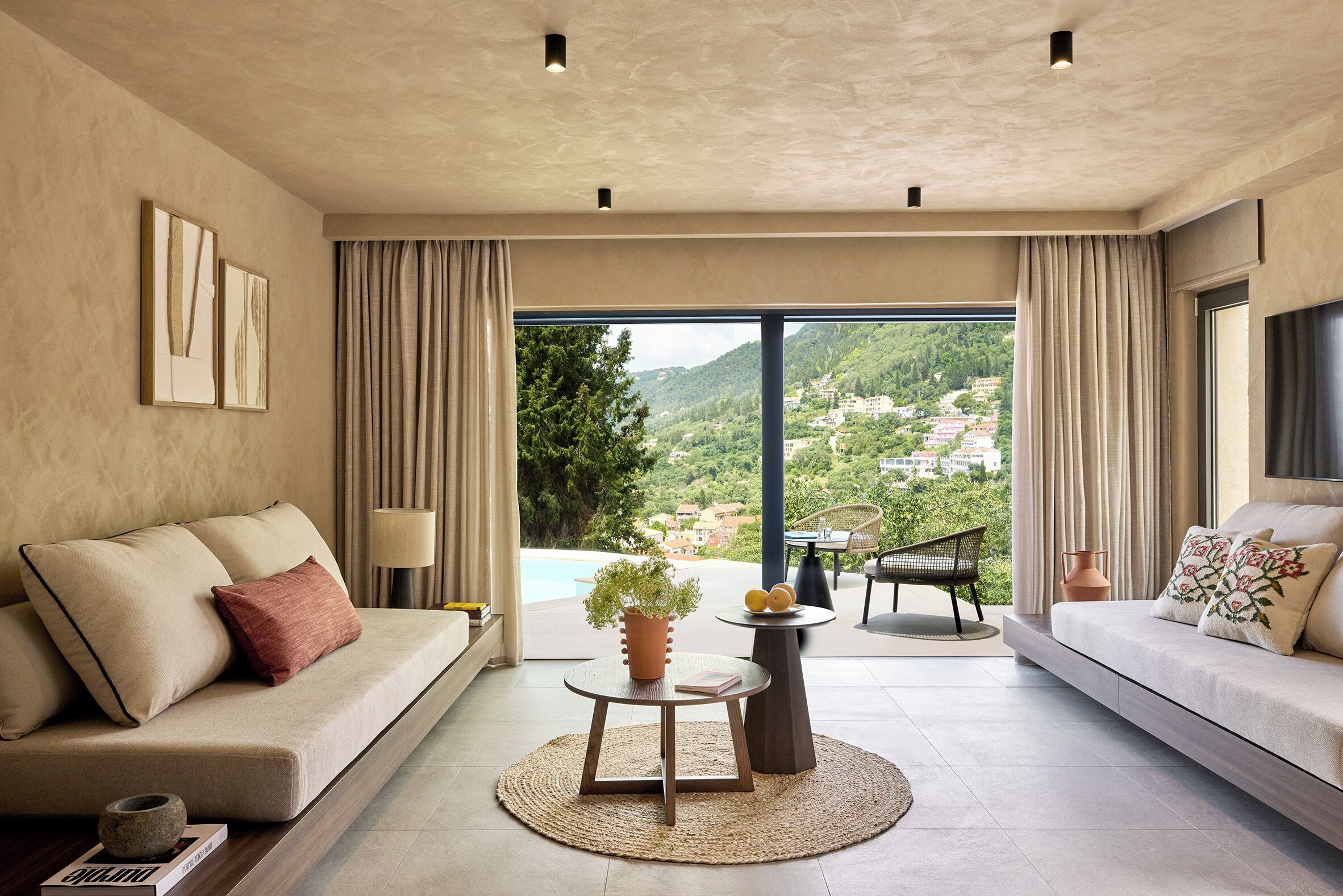 Una sala de estar moderna con sofá, una mesa de centro y vistas a un paisaje montañoso a través de amplios ventanales.