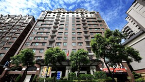 Un hôtel à plusieurs étages doté d’une entrée principale, de balcons et d’un drapeau.