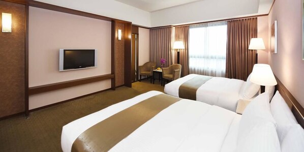 A hotel room with two beds, a TV, a desk, and a chair.