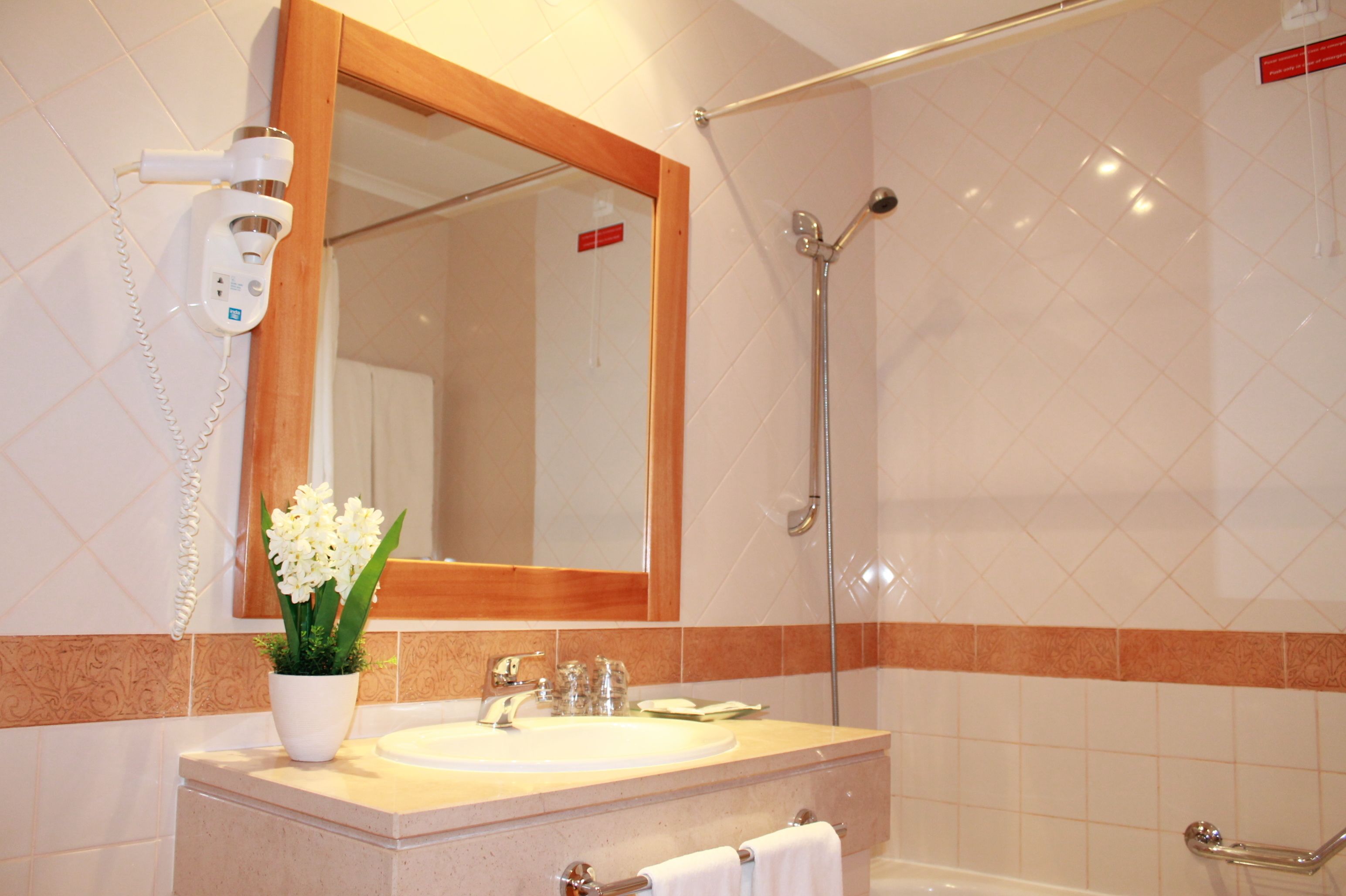 A bathroom with a sink, mirror, and shower.
