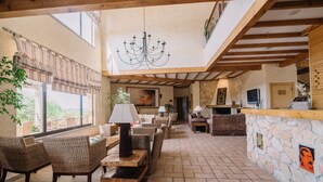 A spacious indoor area with wicker furniture, a stone wall, and a chandelier. - Quinta dos Poetas Nature Hotel & Apartments (Olhao)