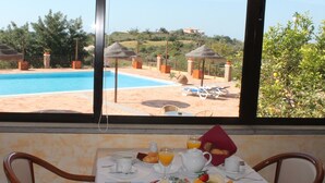 A breakfast table with a view of a swimming pool and umbrellas. - Quinta dos Poetas Nature Hotel & Apartments (Olhao)