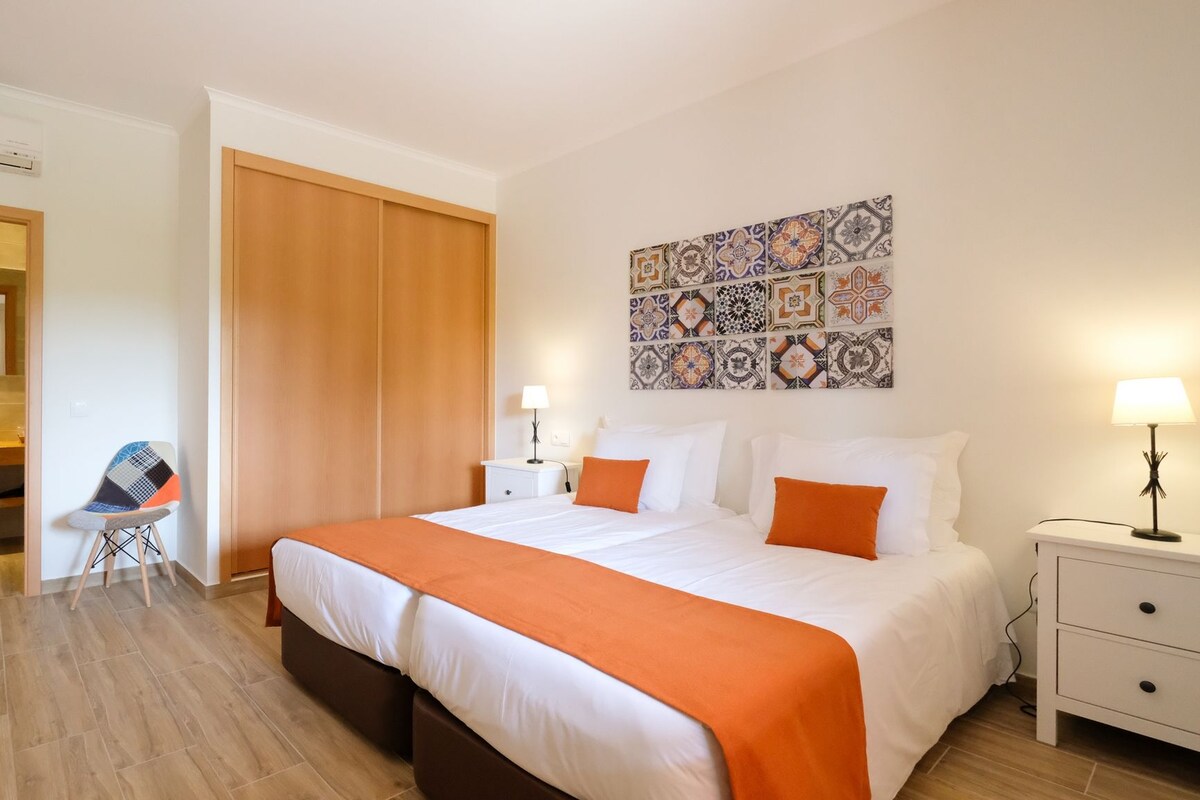 A hotel room with a bed, nightstand, and a wall with decorative tiles.