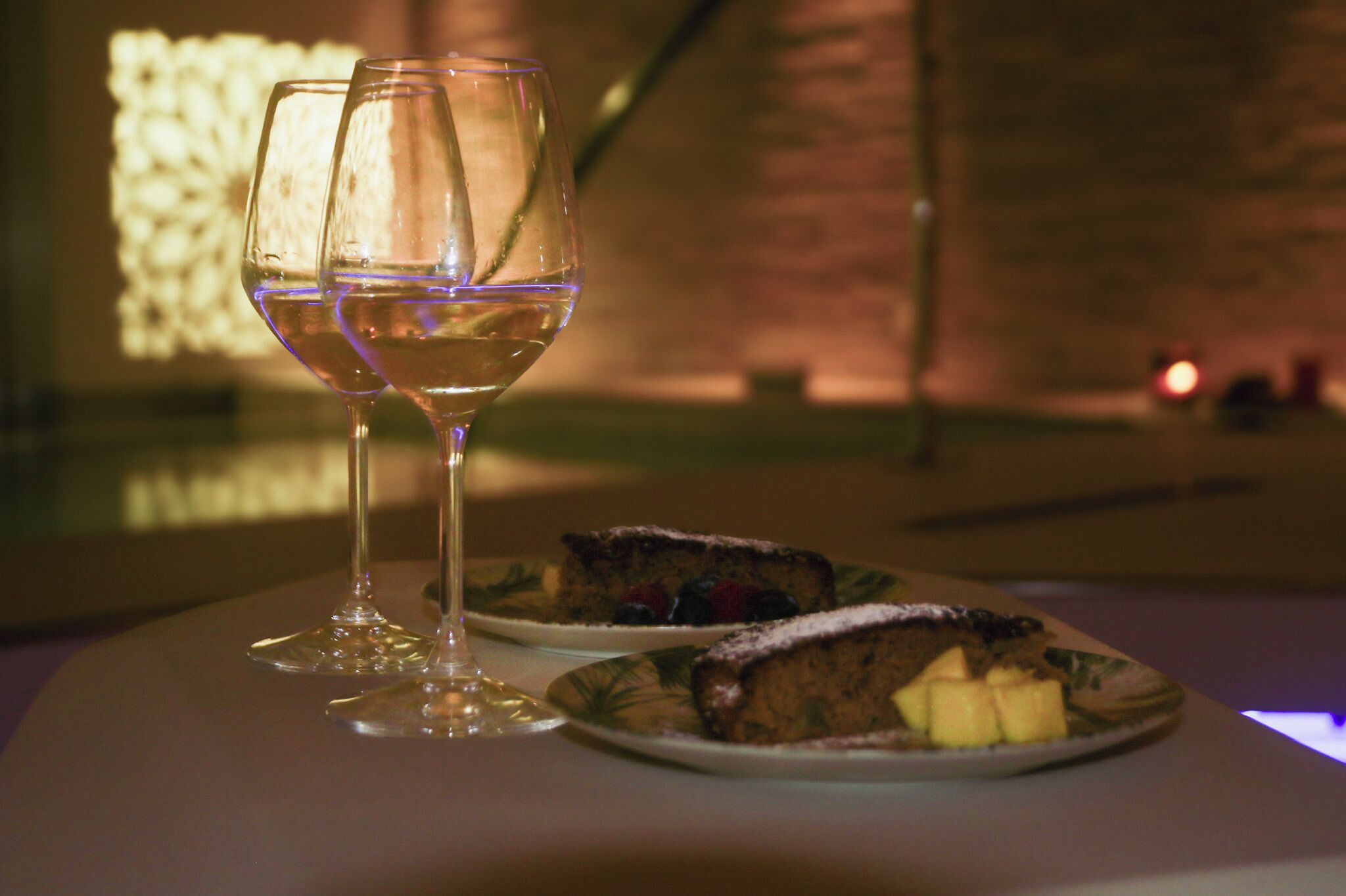 Dos copas de vino y dos platos de postre sobre una mesa.