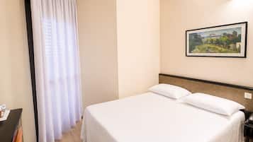 Une chambre d’hôtel avec un lit, une table de chevet, un bureau avec une chaise et un tableau au mur.