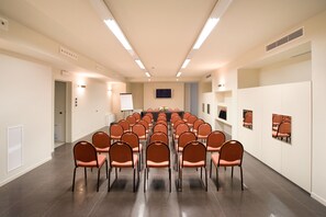 Uma sala de conferências com uma mesa comprida e cadeiras dispostas para uma reunião.