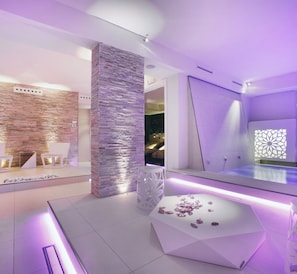 A modern spa area with a stone wall, a reception desk, and a seating area with chairs. - Spa Hotel Parigi 2 (Dalmine)