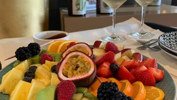 Eine Obstplatte mit verschiedenen Früchten und zwei Gläsern Weißwein auf einem Tisch.
