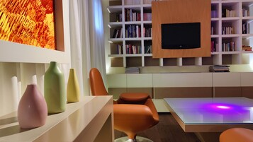 Una camera moderna con una libreria, una televisione a schermo piatto e un tavolo con sedie.