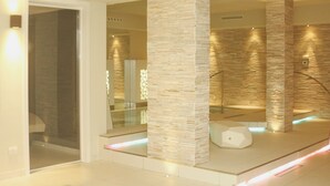 Un moderno espacio de spa con columnas de piedra, divisiones de vidrio y un diseño minimalista.