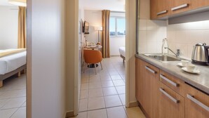 A hotel room with a kitchenette, a dining area with a table and chairs, and a bed. - Residhome Toulouse Occitania (Toulouse)