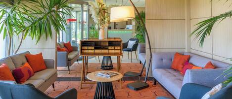 A modern lobby with two sofas, a coffee table, and a reception desk.