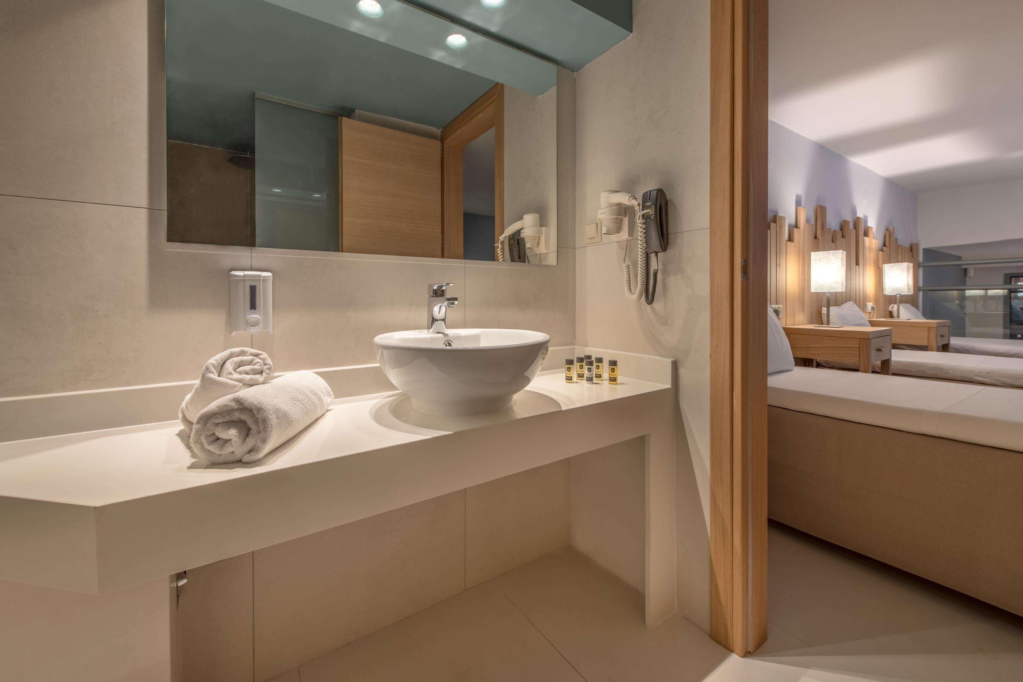 Un baño moderno con un lavamanos grande, un espejo, una toalla y un teléfono.