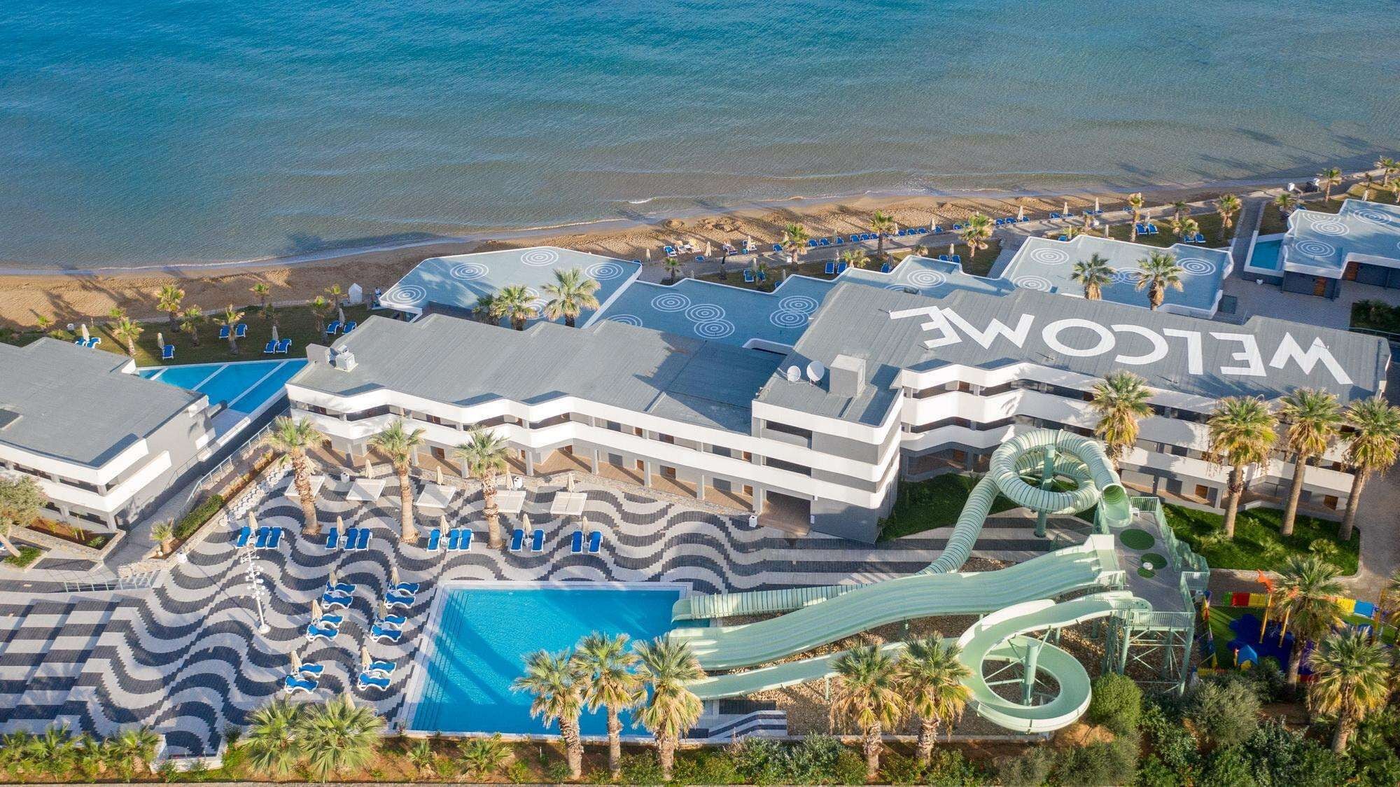 A resort with a large pool, a water slide, and a 'WELCOME' sign.