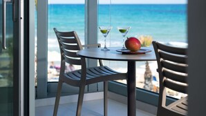 Een balkon met een tafel, twee stoelen en uitzicht op de oceaan.
