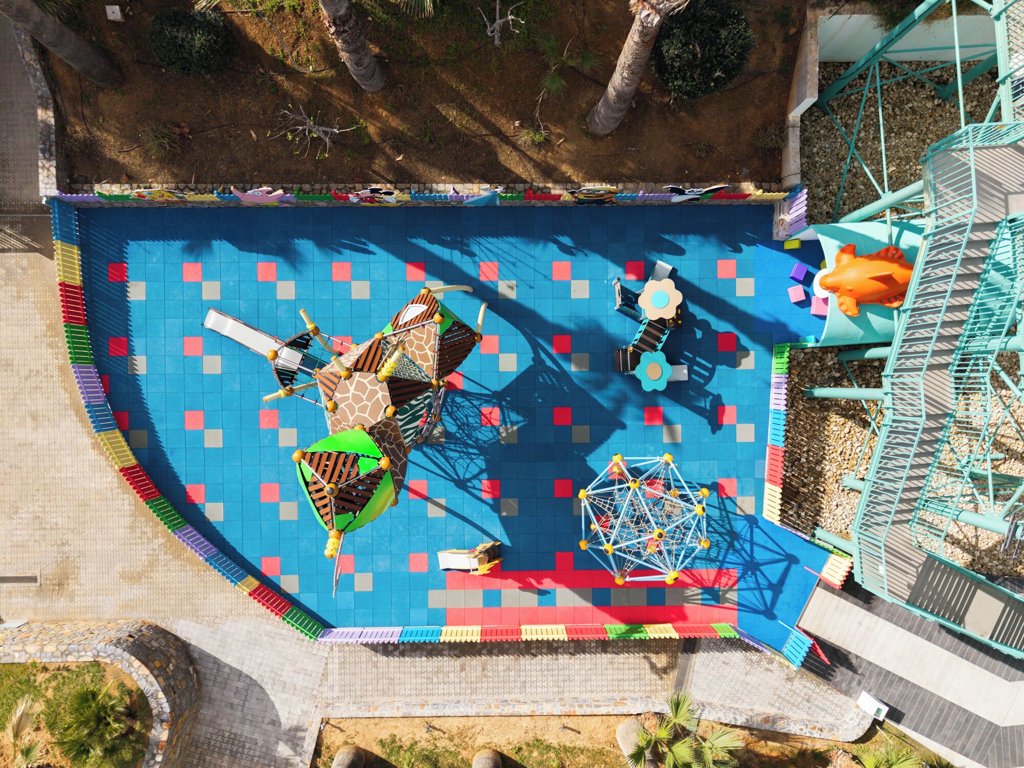 A playground with various play structures, including a slide, swings, and climbing areas.