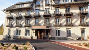 Un hotel grande de varios pisos con un estilo arquitectónico europeo tradicional, con balcones y un letrero que dice "HOTEL LE CONTINENTAL".