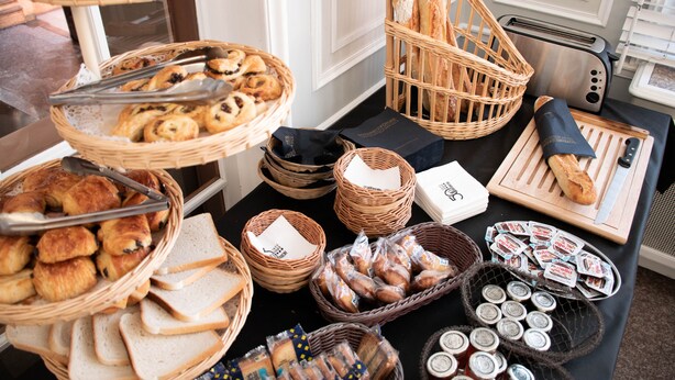 Una mesa de bufé con diversos alimentos, incluyendo pan, pasteles y productos envasados.