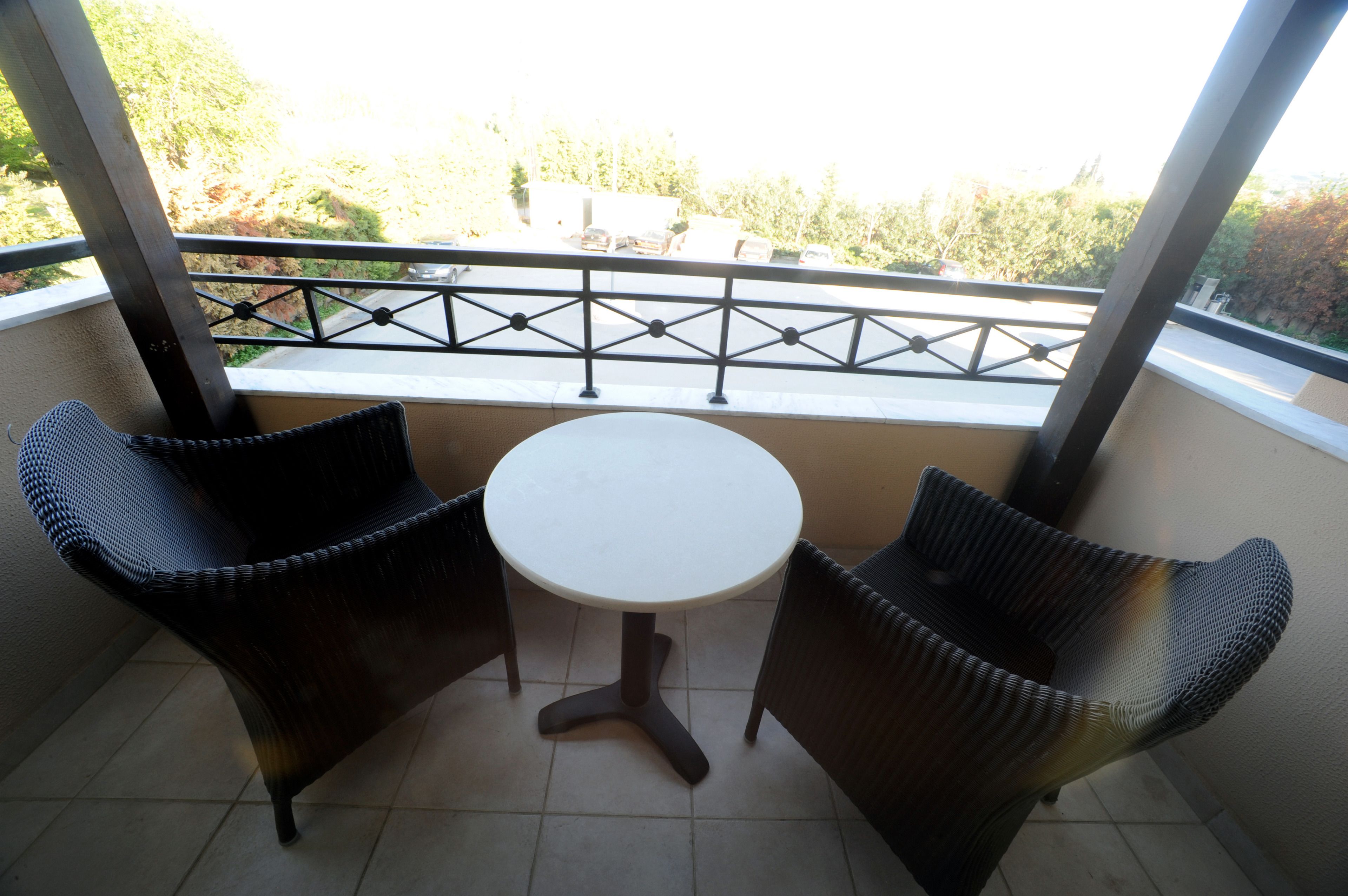 A balcony with two wicker chairs and a small round table.