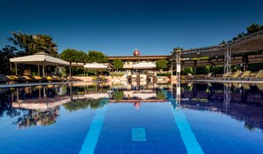 Un hotel con piscina, tumbonas y sombrillas.