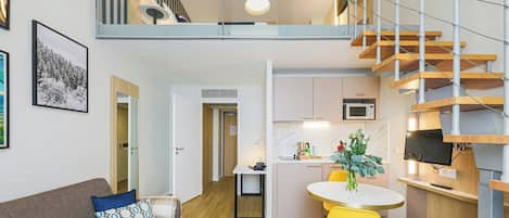 A loft-style apartment with a kitchen, dining area, and a staircase leading to an upper level.