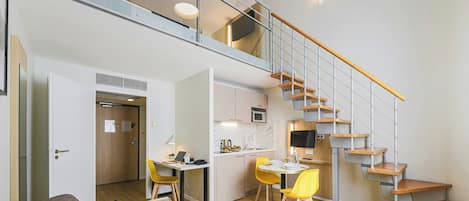 Un apartamento moderno con un dormitorio en loft, comedor y cocina.
