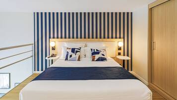 A hotel room with a bed, bedside tables, a wooden wardrobe, and a striped wall.