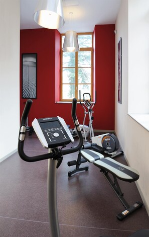 A home gym with an elliptical machine, a stationary bike, and a treadmill.