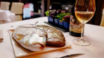 A dining table with two whole fish, a wine glass, and a bottle of wine.