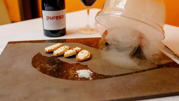 Una mesa con una botella de vino, una copa de vino tinto y un plato con pan y una sustancia blanca.
