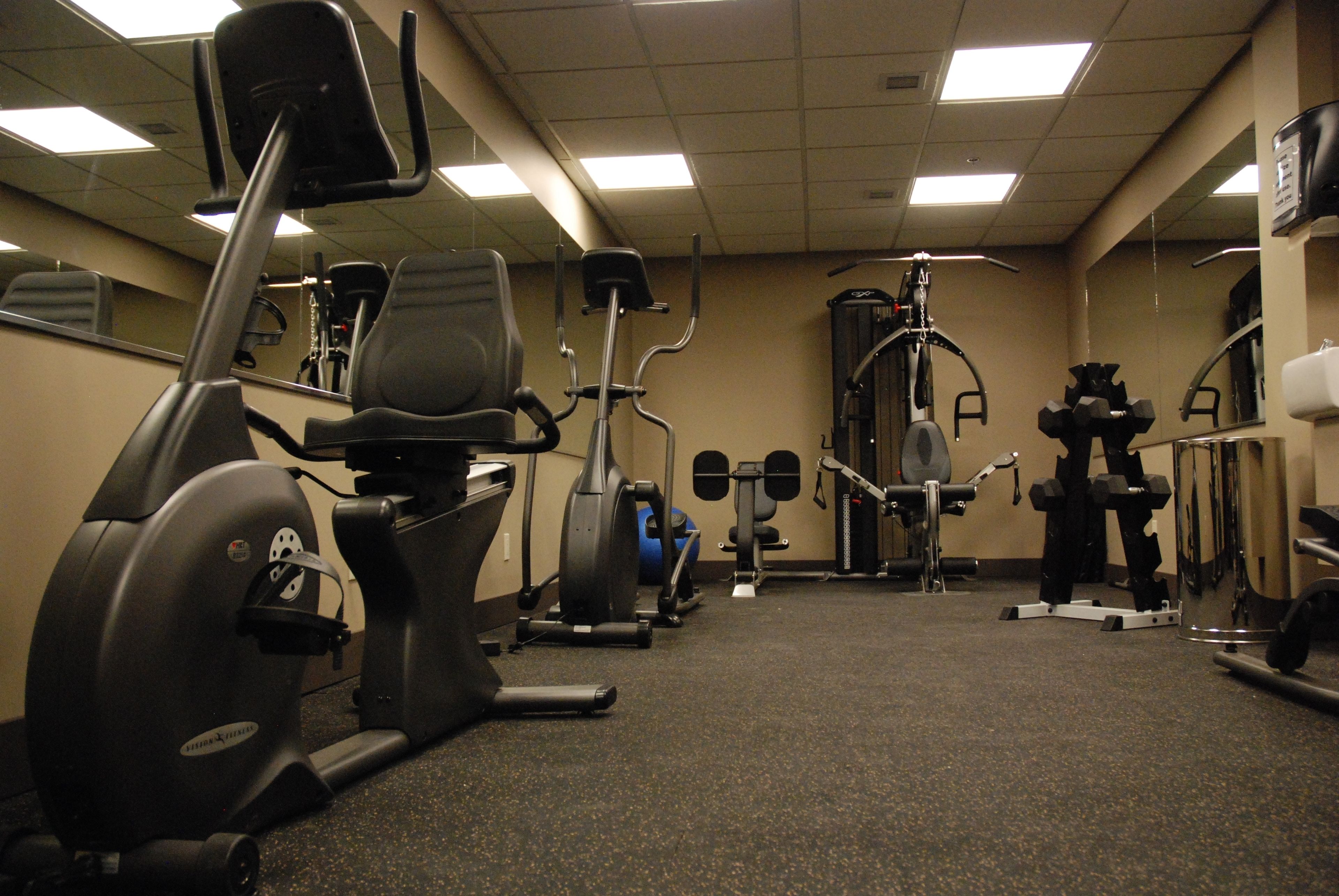 A gym with stationary bikes, elliptical machines, and weightlifting equipment.