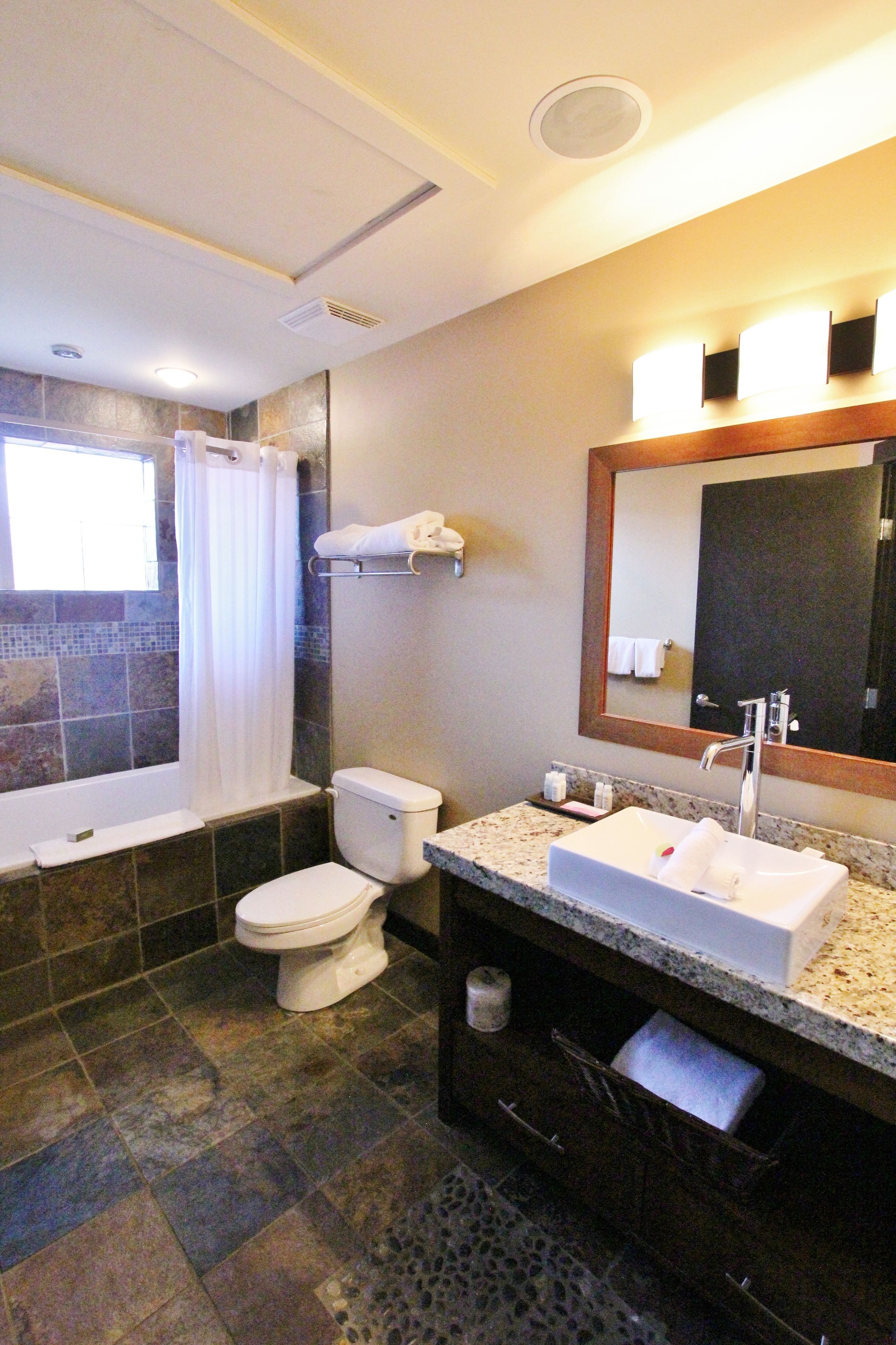 A bathroom with a bathtub, toilet, sink, and a mirror.