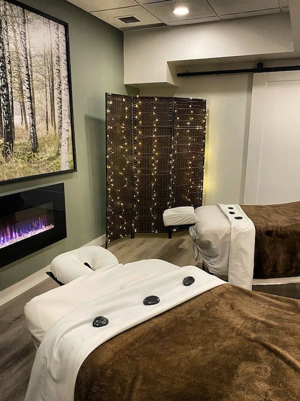 Relax in a serene spa room with a massage table, wall-mounted screen, and ambient lighting.