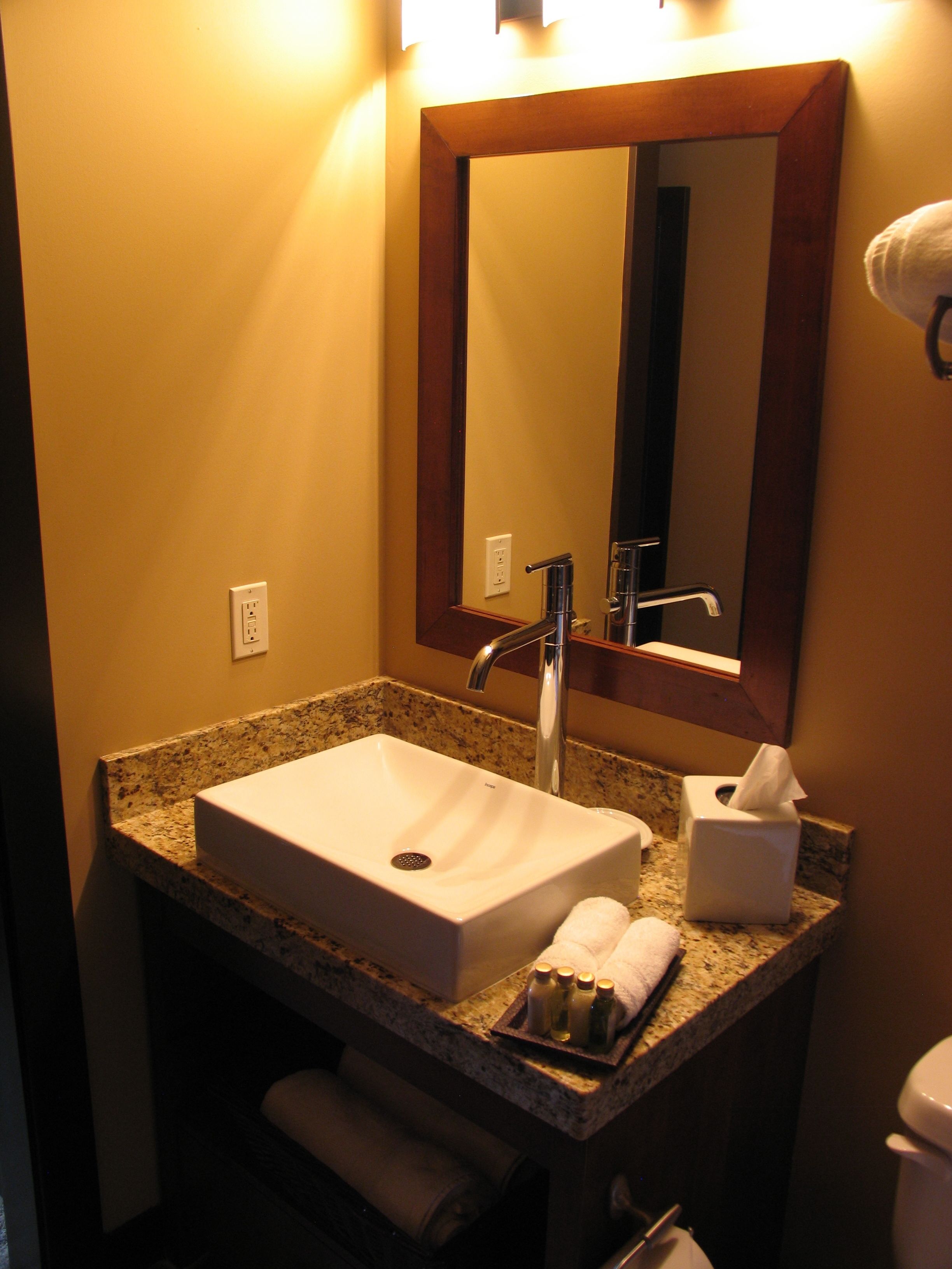 Baño con lavamanos blanco, espejo y dispensador de toallas.